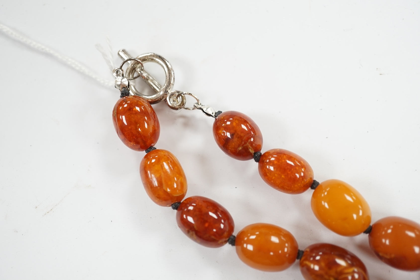 A single strand graduated oval amber bead necklace, 76cm, gross weight 107 grams. Condition - poor